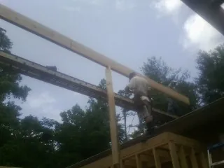 Carpenter setting a ridge beam over a new addition frame — Ice Dam Removal by Roofing Brothers in Evant