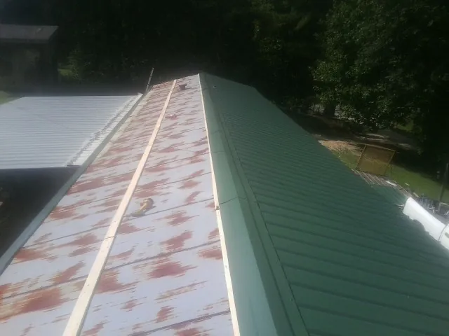 Old rusted panels beside newly installed green metal roofing — Wind Damage Roof Repair by Roofing Brothers in Evant
