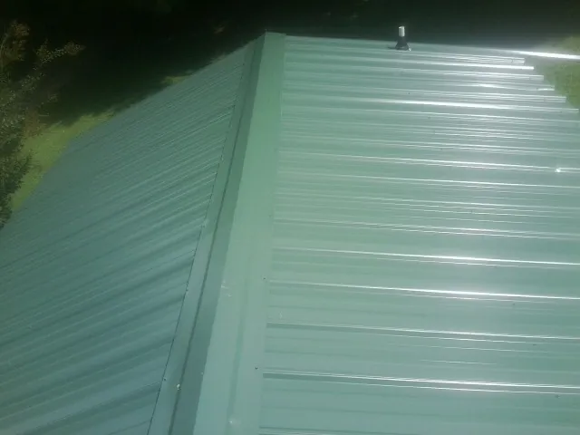New green metal panels meeting at the ridge of a roof — Flat Roof Repair work by our crew in Evant
