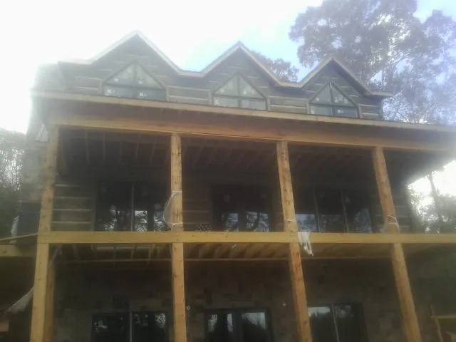 Dormers and porch framing on a large log home under construction — Roof Coating work by our crew in Evant