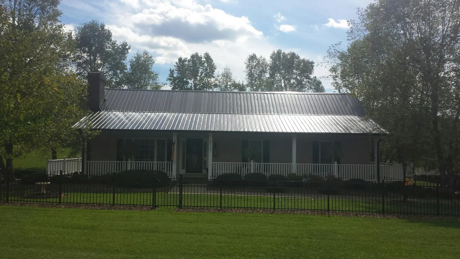Gray metal roof on a brick ranch with a full width front porch — Gutter Guard Installation work by our crew in Evant