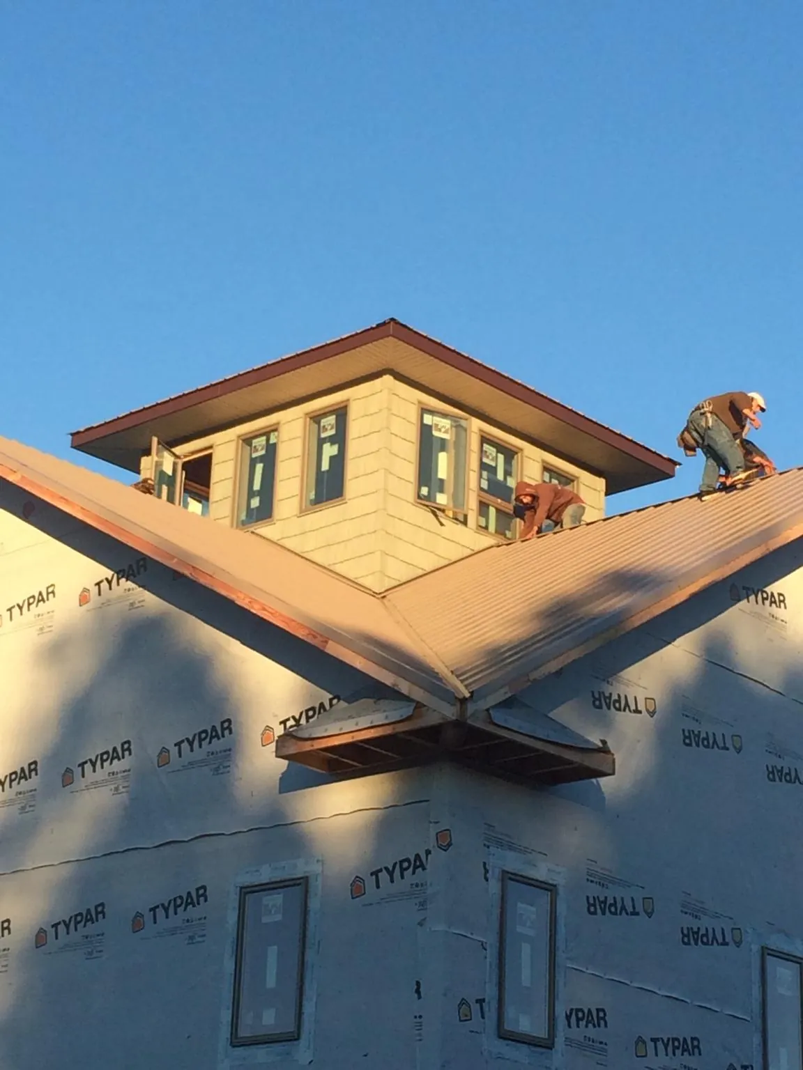 Roofers working around a rooftop cupola on a new metal roof at sunset — Roof Waterproofing in Evant by Roofing Brothers